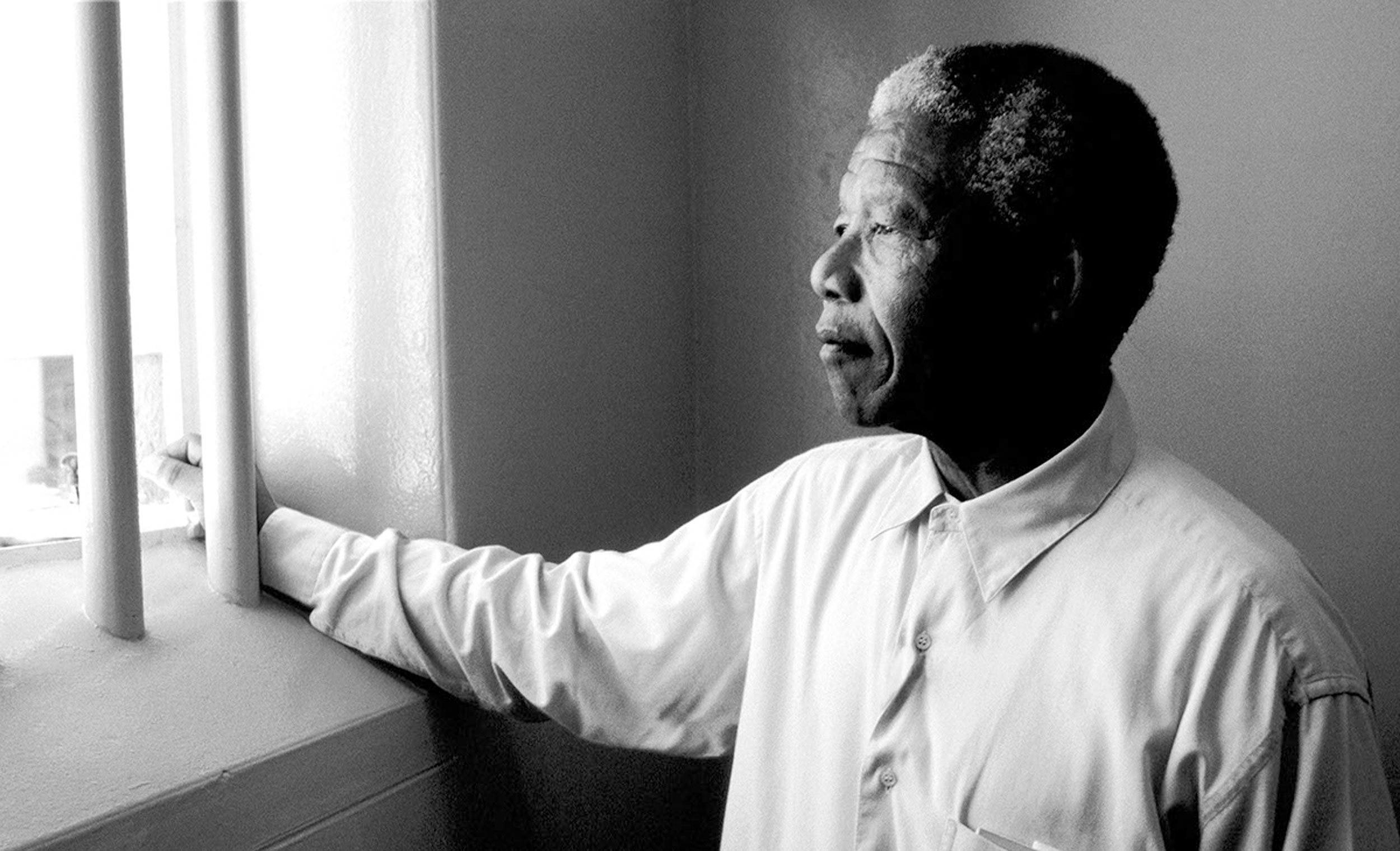 1994, Sudáfrica. Nelson Mandela mira a través de la ventana barrada de la que fue su celda durante 27 años. Imagen de © David Turnley/CORBIS